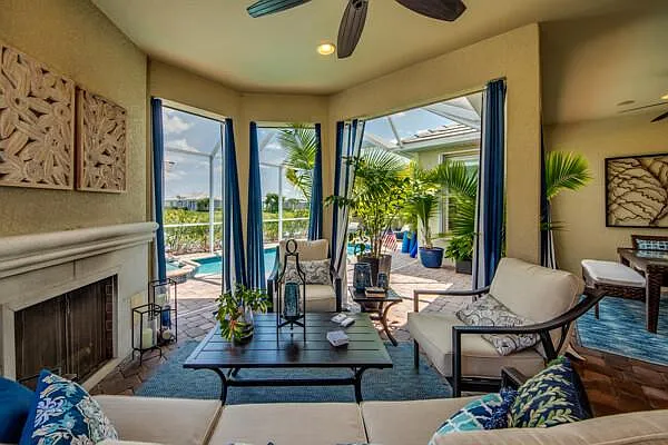Screened lanai sitting area with gas fireplace, white sofas, and pool view